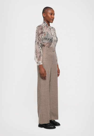 Durchsichtige Bluse mit Knopfleiste und architektonischem Print in Grau und Beige, kombiniert mit hochtaillierten, karierte weitem Hosen in Braun und Schwarz.