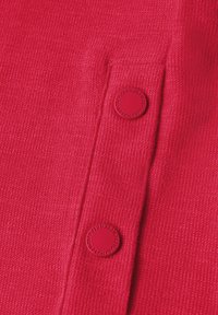 Rød tekstureret stof med to cirkulære røde knapper. Stoffet har et vævet mønster, og knapperne har præget detaljer.