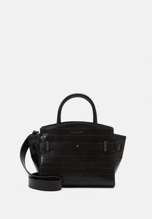 Černá kabelka s krokodýlí texturou, s horními rukojeťmi, odnímatelným ramenním popruhem a logem Calvin Klein na přední straně.