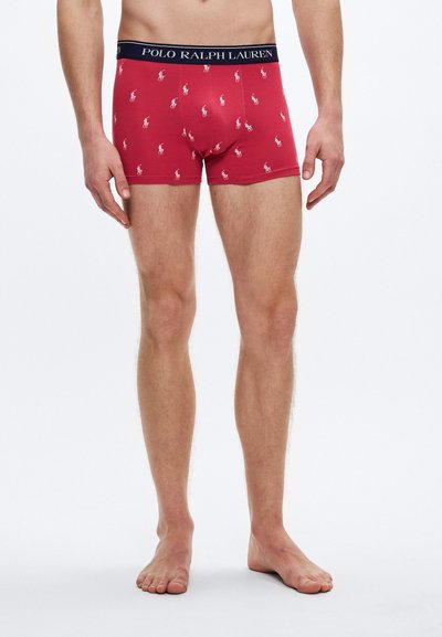Boxeri roșii cu un design cu modele mici al logo-urilor polo albe, având o talie bleumarin cu inscripția "POLO RALPH LAUREN".