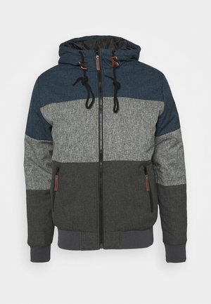 Chaqueta con capucha que presenta un diseño de bloques de color en azul oscuro, gris y carbón. Incluye cierre de cremallera y cordones de contraste.