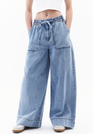 Light blue denim wide-leg trousers with an elastic waistband, drawstring, and two front pockets; visible stitching and relaxed fit.