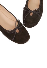 Brown suede ballet flats with a rounded toe, decorative bow, and cut-out detail. Smooth interior lining, soft texture, and minimalistic design.
