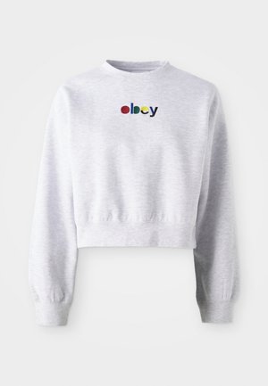 Kuttet grå hettegenser laget av myk stoff, med rund hals og lange ermer med ribbestrikkede mansjetter. "Obey" logo brodert i flere farger.