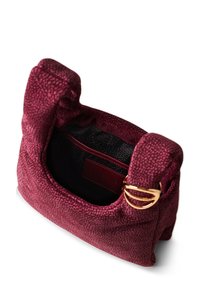 Burgunderfarbene, strukturierte Stofftasche mit zwei kurzen Griffen, goldenen Hardware-Details und einem schwarzen Inneren, das ein Logo und eine Reißverschlusstasche aufweist.