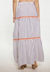Gonna maxi con righe verticali viola e bianche, caratterizzata da una fascia ricamata arancione intorno alla vita e un design a strati.