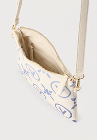 Lille cremefarvet crossbody taske med lys blå abstrakt mønster, lynlåsåbning i toppen og aftagelig rem med guldfarvede detaljer.