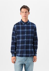 Navy blue plaid shirt with blue and white accents, buttoned front, and a collar. Made from a soft, textured fabric with long sleeves.