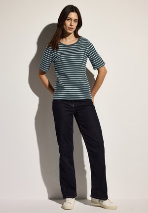 Gestreiftes Baumwoll-T-Shirt in Türkis und Weiß, mit rundem Halsausschnitt und kurzen Ärmeln, kombiniert mit dunkelblauen Denim-Jeans und weißen Sneakers.