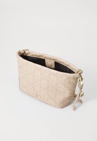 Beige skulderveske med preget mønster, gullfargede detaljer og svart innvendig. Har trykknappåpning og justerbar stropp.