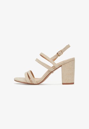 Beżowe sandały na wysokim obcasie z plecionymi paskami materiałowymi, otwartym noskiem i masywnym słupkowym obcasem. Zapięcie na klamrę przy pasku na kostce. Teksturowana powierzchnia.