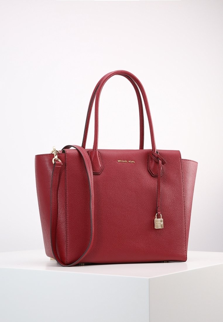 Sac cabas en cuir rouge texturé avec double poignée, bandoulière amovible et petit charm cadenas doré à l’avant.
