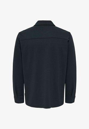 Svart långärmad skjorta med krage. Har en mjuk textur och en yoke-detalj över ryggen för extra design.