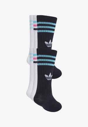 Dwie pary skarpetek Adidas, jedna czarna z niebieskimi paskami i logo, a druga biała z niebieskimi i różowymi paskami, przedstawione na białym tle.