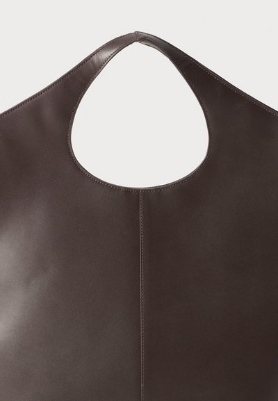 Mörkbrun läder tote-väska med ett brett, rundat cut-out-handtag. Slät textur med en ren, minimalistisk design och sydda sömmar.