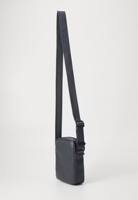 Melnas crossbody soma, izgatavota no gludas materiāla, ar taisnstūra formu, regulējamu siksnu un minimālistisku dizainu.