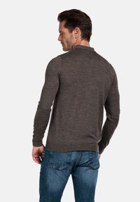Donkergrijze lange mouwen trui met een ronde kraag, gestructureerde stof en een getailleerd ontwerp, gecombineerd met lichtblauwe denim jeans.