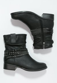 Botines negros de imitación cuero con diseño arrugado, detalles de correas con tachuelas, cremallera lateral y tacón apilado para mayor estabilidad.