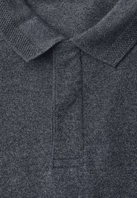 Tmavě šedá pletená polokošile s texturovaným límcem a knoflíkovou légou, zobrazující podrobnou strukturu tkaniny a šití.