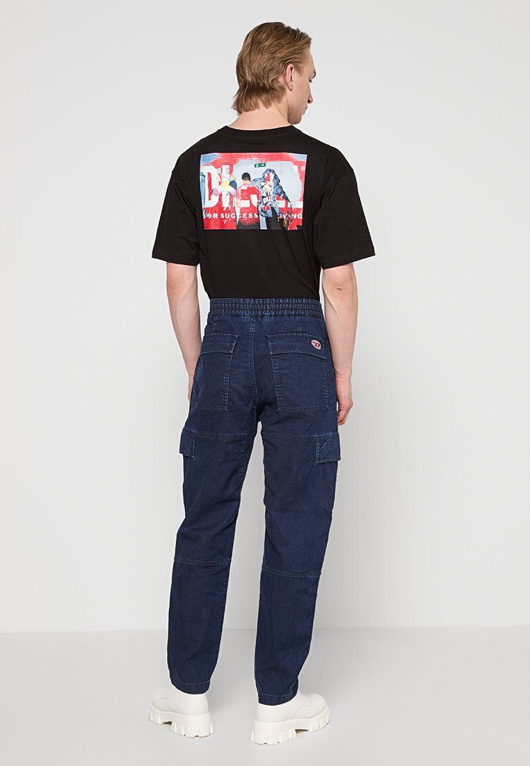 Zwarte T-shirt met een kleurrijke grafische print op de achterkant, gecombineerd met donkerblauwe cargo-broeken met zakken en een elastische tailleband.