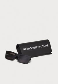 Black rectangular sunglasses with dark lenses, featuring thick edges and a glossy finish, accompanied by a black case labeled "RETROSUPERFUTURE."