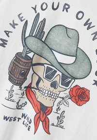 Grafisches T-Shirt mit einem Schädel in Sonnenbrille, grünem Hut, rotem Bandana und Rose, umgeben von Kakteen und dem Text "GESTALTE DEIN EIGENES WILD-WEST-LEBEN."