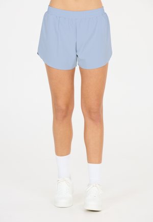 Helle blaue Sportshorts mit elastischem Bund, mit einer glatten Textur und lockerer Passform, kombiniert mit weißen Sneakers und Socken.