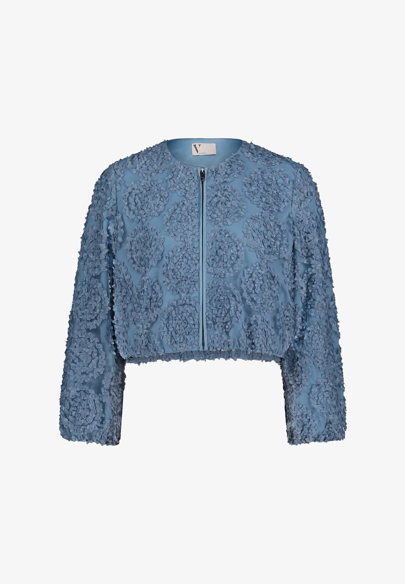 Veste courte en tissu bleu clair avec applications florales texturées, manches longues, et fermeture éclair à l'avant. Présente un col rond.