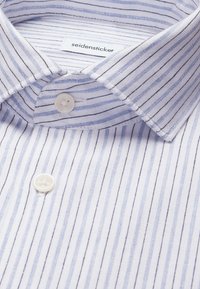 Col de chemise rayé blanc et bleu clair avec boutons blancs et étiquette de marque « seidensticker » à l’intérieur du col.