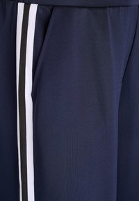 Námorné športové šortky s bielymi a čiernymi bočnými pruhmi, vyrobené z hladkej tkaniny s voľným strihom a elastickým pásom.