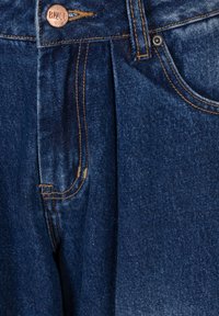 Granatowe dżinsy z plisowanym przodem, kontrastowymi pomarańczowymi szwami i miedzianym guzikiem z nazwą marki Bizuu.