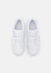 Baskets Nike blanches avec une tige en cuir lisse, un bout perforé pour la ventilation, des lacets plats et des semelles rembourrées pour le confort.