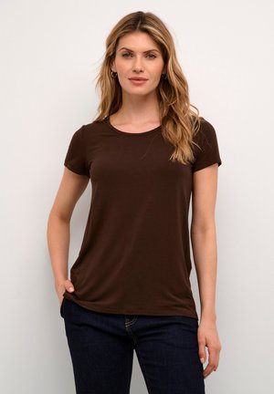 Camiseta marrón de manga corta con cuello redondo y textura suave. Combina con jeans oscuros, creando un look sencillo y casual.
