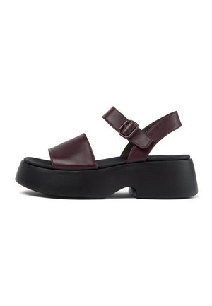 Burgundy leather sandals with a wide toe strap, adjustable ankle buckle, and a thick black platform sole. Smooth texture, modern design.