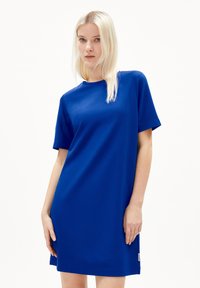 Kort blå bomulls-klänning med korta ärmar, rund halsringning och rak skärning. Har en liten etikett på fållen.