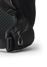 Sac à dos noir avec une poche latérale en maille texturée, fermeture à glissière et bretelle réglable. Caractérisé par des matériaux durables et un design minimaliste.