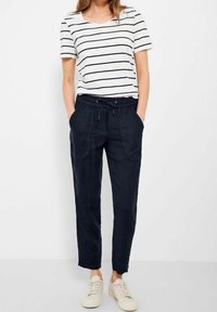 Biała koszulka z granatowymi poziomymi paskami, w połączeniu z granatowymi spodniami z troczkami. Spodnie mają dwie kieszenie z przodu i luźny krój.