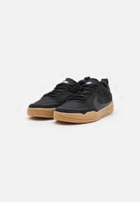 Black sneakers with a textured mesh upper and suede accents. Rubber gum sole, flat laces, and a swoosh logo on the side.