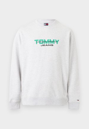 Svjetlosiva majica s okruglim izrezom s zelenim tekstom "TOMMY", manjim crnim tekstom "Los Angeles, Worldwide" iznad i "JEANS" ispod, na sredini prednje strane.