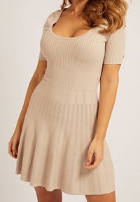Abito beige a coste con maniche corte, scollatura a girocollo, corpino aderente e gonna svasata. Presenta una trama verticale e dettagli sottili.