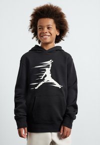 Felpa nera con cappuccio che presenta un grande logo Jumpman bianco sfocato. Ha una tasca frontale e una vestibilità comoda, realizzata in tessuto morbido.
