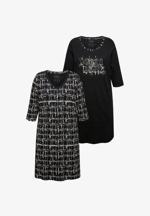 Tunika w czarno-białe wzory, jedna z dekoltem w serek i wzorem w kratkę, druga w jednolitym czarnym kolorze z napisem "Dobranoc". Obie mają rękawy o długości trzech ćwiartek.