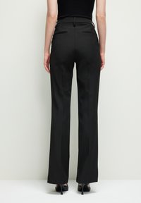 Zwarte, hooggeprofileerde broek met een op maat gemaakte pasvorm en rechte pijpen. Beschikt over twee achterzakken en een gladde, strakke textuur.