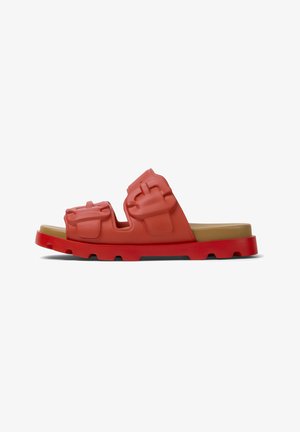 Red rubber slide sandal with a thick red sole, featuring raised decorations on the straps and a smooth, beige footbed.