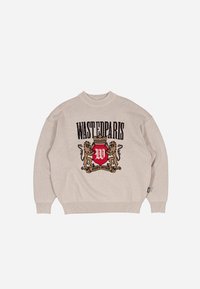 Suéter beige con un gran estampado negro de "WASTEDPARIS", un escudo rojo con leones y el texto "ALWAYS FAITHFUL" debajo, con textura de punto.