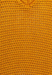 Gul virkad tyg med en tät struktur och små mellanrum, som visar ett stickat mönster och en mjuk, flexibel känsla.
