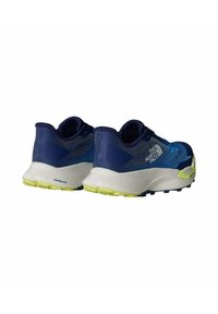 Zapatillas de running azules con parte superior de malla texturizada, mediasuela blanca y suela exterior amarillo-verde. Presenta marcas en el lateral y acentos en el talón.