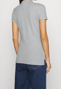 Szary krótki rękaw polo z miękką teksturą, z klasycznym kołnierzykiem i bocznymi rozcięciami dla większej swobody ruchów.