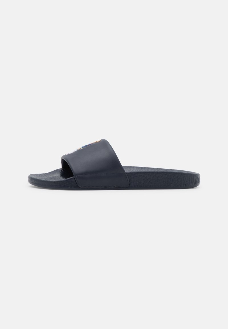Une sandale slide bleu marine unique avec une large bride sur le dessus et une semelle texturée, vue de côté sur fond blanc.