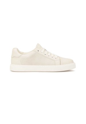Zapatilla blanca de cuero con detalles perforados en los laterales, suela de goma y cordones planos. Presenta un acabado suave y un diseño de punta redondeada.
